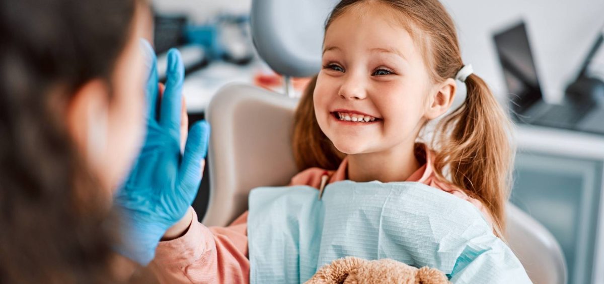 niña sonriendo y chocando los cinco con dentista